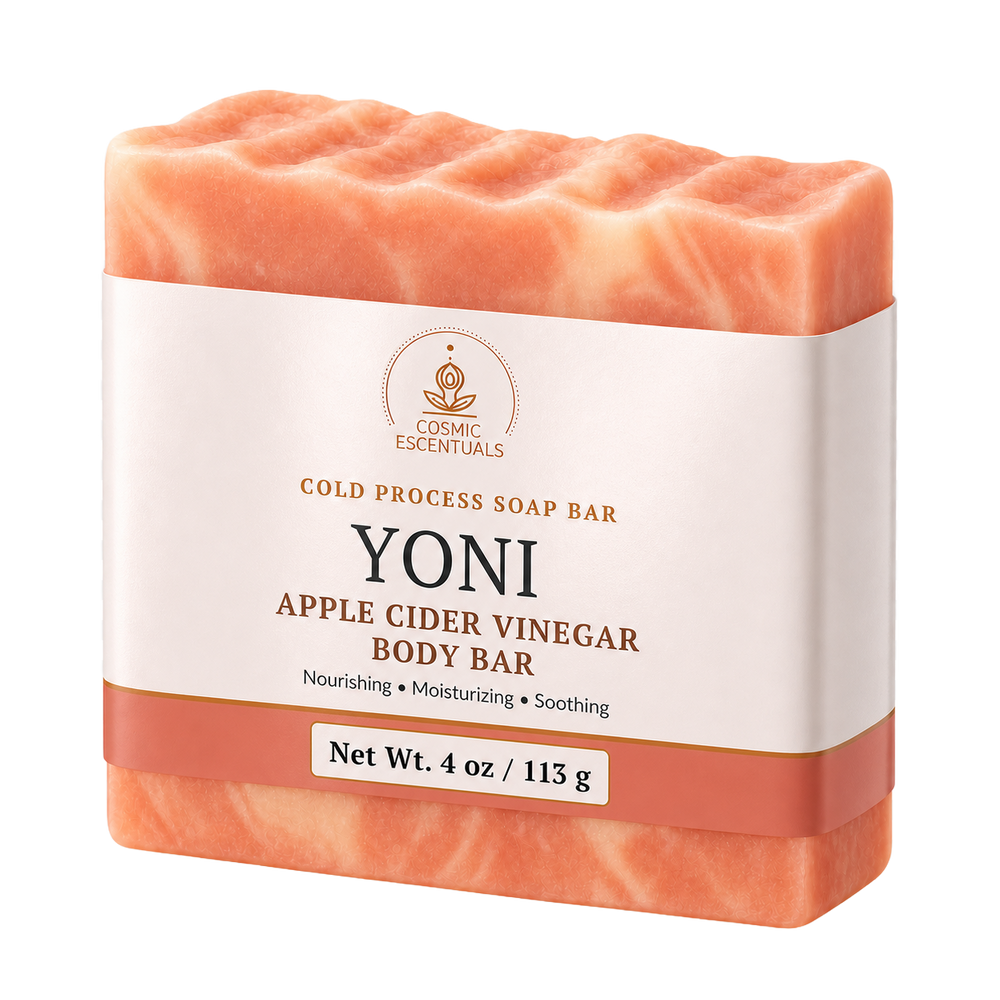 A single bar of Cosmic Essentials Yoni Apple Cider Vinegar Body Bar soap, shown in a peachy-orange color with a white paper label band around the middle, on a solid white background.