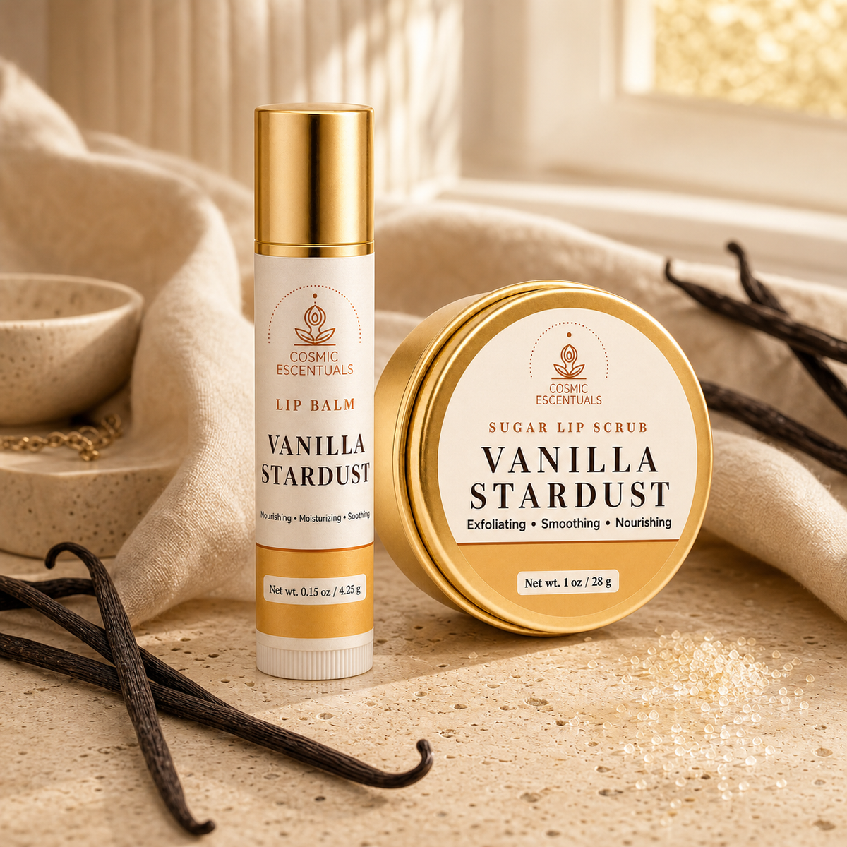 A cosmetic lip balm and matching lip scrub tin from Cosmic Escentuals, both labeled Vanilla Stardust, styled on a warm beige surface with draped fabric, scattered vanilla beans, and soft natural light.