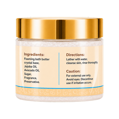 Foaming bath butter in a clear jar with a shiny gold lid and a cream-colored label containing product instructions and ingredients.