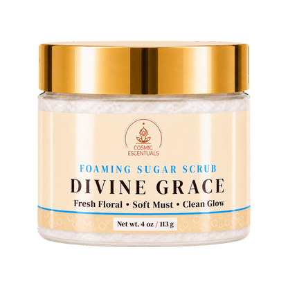 A jar of Divine Grace Foaming Sugar Scrub by Cosmic Essentials, featuring a shiny gold lid and a cream-colored label with blue and black text, set against a plain white background.