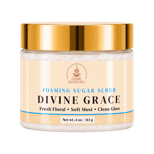 A jar of Divine Grace Foaming Sugar Scrub by Cosmic Essentials, featuring a shiny gold lid and a cream-colored label with blue and black text, set against a plain white background.