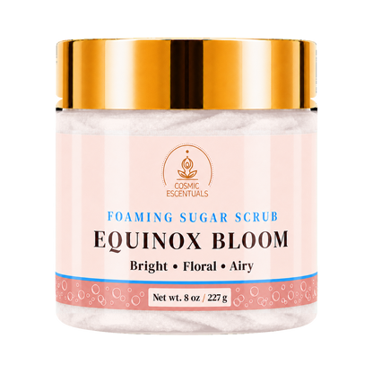 Cosmic Essentials Equinox Bloom Foaming Sugar Scrub in a clear jar with a metallic gold lid and a light pink label, set against a plain white background.