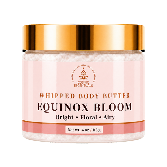 Cosmic Essentials Whipped Body Butter in Equinox Bloom scent, in a clear jar with a metallic gold lid and a light pink label, on a white background.