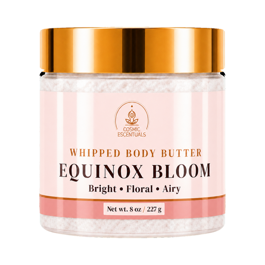 A jar of Cosmic Essentials Whipped Body Butter in the Equinox Bloom scent, featuring a metallic gold lid and a pale pink label with white whipped body butter visible inside.