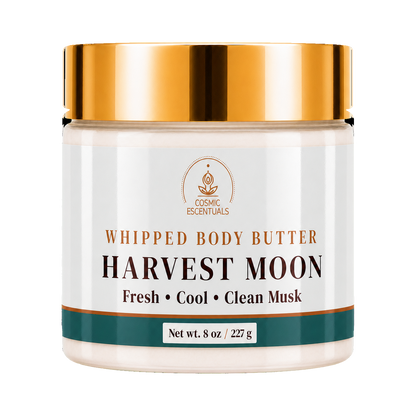 A jar of Cosmic Essentials Whipped Body Butter, Harvest Moon, with a metallic gold lid and a white label featuring brown and dark green text and accents.