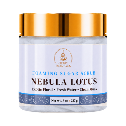 Cosmic Essentials Nebula Lotus Foaming Sugar Scrub in a clear jar with a metallic gold lid and a white label with blue and brown text.