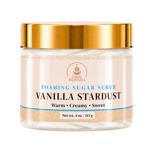 A jar of Cosmic Essentials Vanilla Stardust Foaming Sugar Scrub with a shiny gold lid and a cream-colored label, shown on a plain white background.