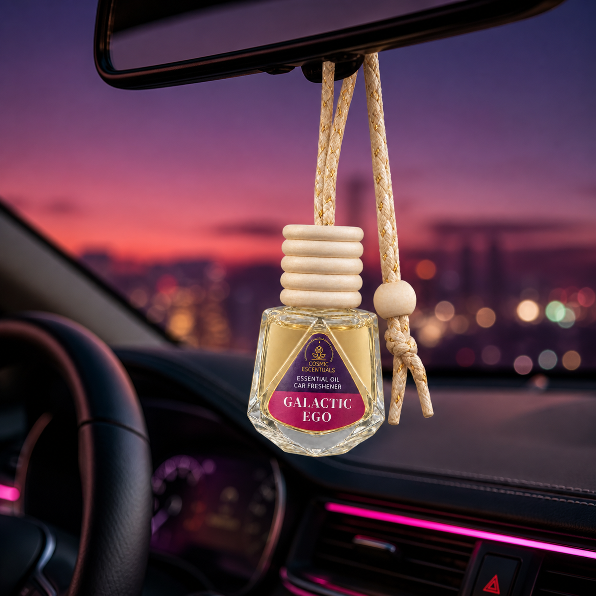 Galactic Ego Essential Oil Car Freshener hanging from a rearview mirror at dusk.